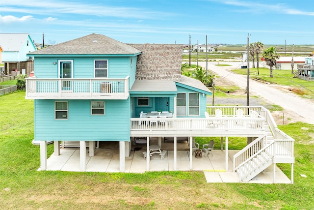 back of house featuring a balcony, a patio, a wooden deck, and a yard