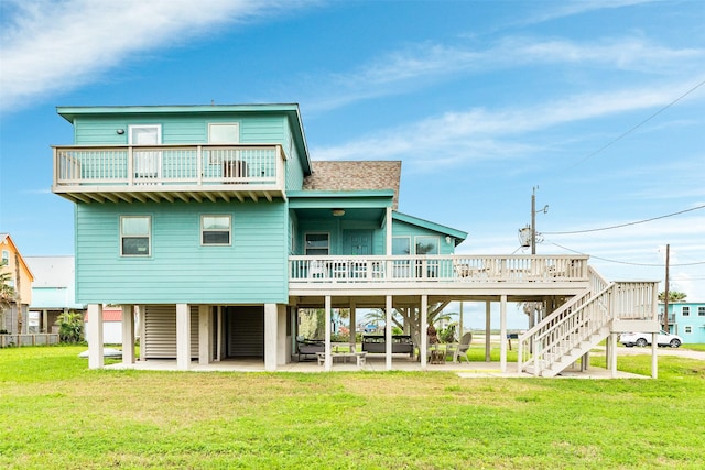 rear view of property featuring a patio, a wooden deck, a yard, a shingled roof, and stairs