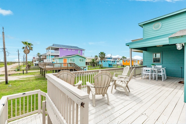 deck featuring outdoor dining area, a residential view, and a lawn