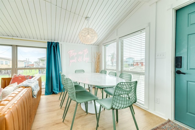 dining space with light wood finished floors, plenty of natural light, and vaulted ceiling