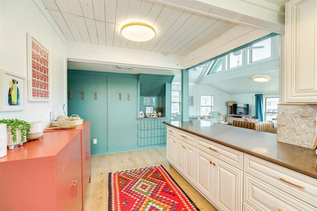 kitchen featuring tasteful backsplash, open floor plan, lofted ceiling with beams, and light wood-type flooring