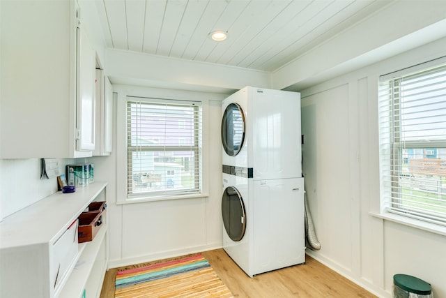 washroom with light wood finished floors, stacked washer / dryer, laundry area, and wood ceiling