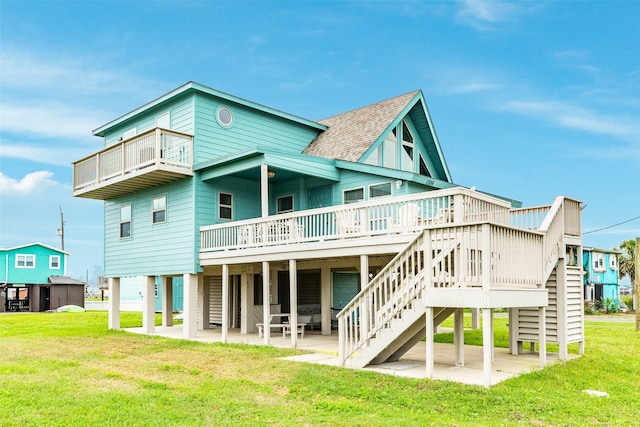 back of property with a yard, stairway, a shingled roof, and a patio