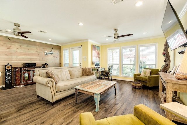 living room with wood-type flooring, wooden walls, ornamental molding, and ceiling fan