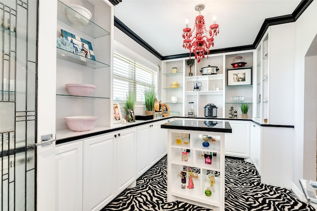 kitchen with white cabinets, ornamental molding, and a chandelier