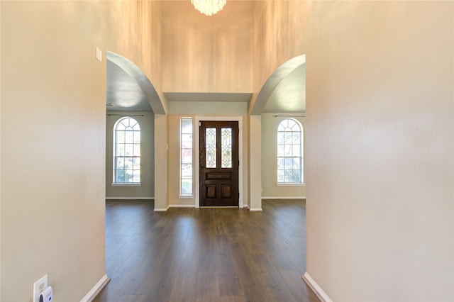 foyer featuring a towering ceiling, dark wood-type flooring, and a chandelier