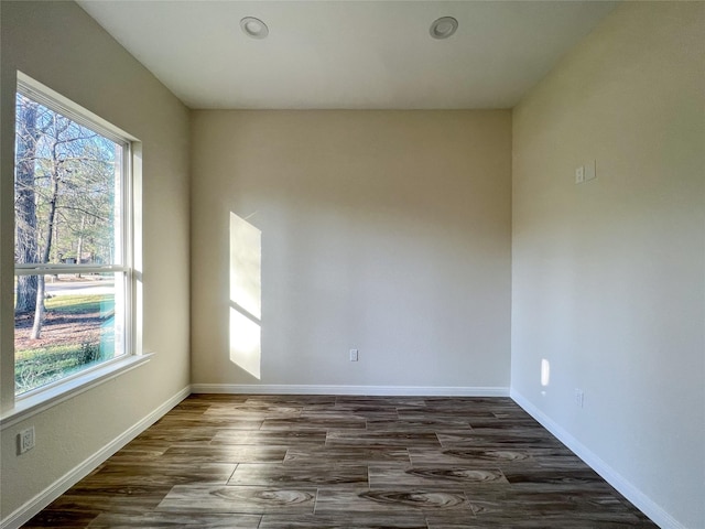 unfurnished room featuring a wealth of natural light and dark hardwood / wood-style floors