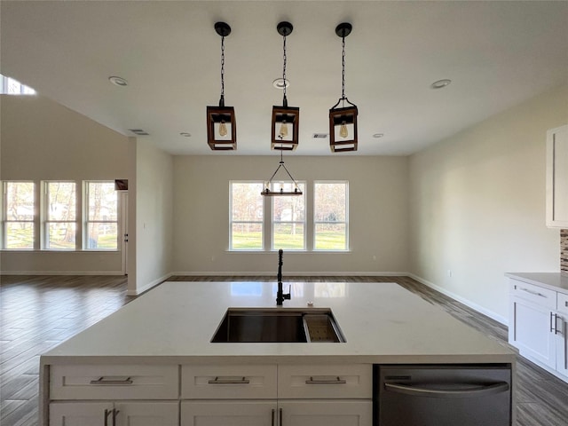 kitchen featuring sink, decorative light fixtures, white cabinetry, dishwasher, and a kitchen island with sink