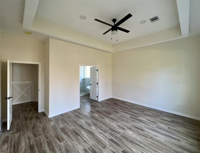 empty room featuring wood-type flooring, a raised ceiling, and ceiling fan