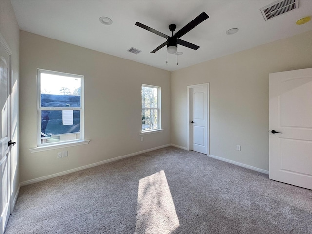 unfurnished room with ceiling fan, light carpet, and plenty of natural light