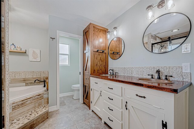 bathroom with vanity, tile patterned floors, tiled bath, and toilet