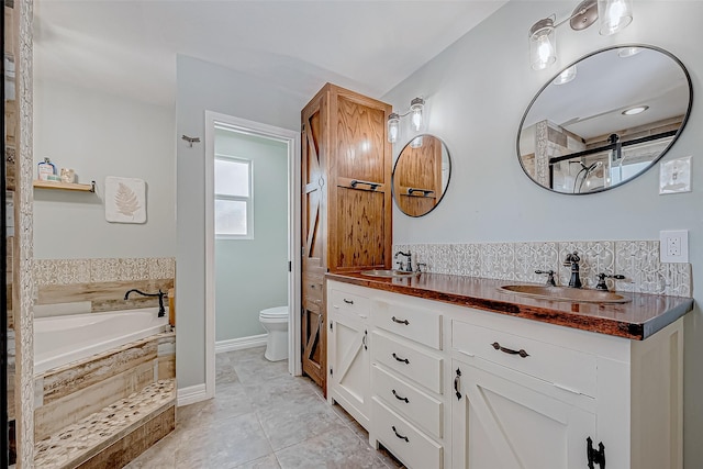 bathroom with tiled tub, vanity, tile patterned flooring, and toilet