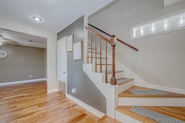 staircase featuring a textured ceiling and hardwood / wood-style floors