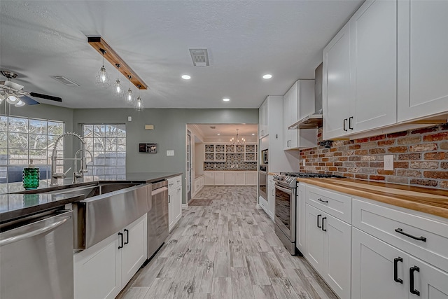 kitchen with appliances with stainless steel finishes, hanging light fixtures, white cabinets, and sink