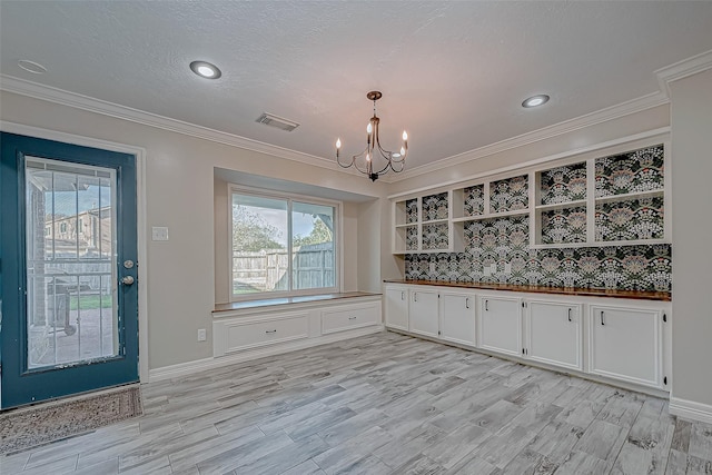 unfurnished dining area with an inviting chandelier, ornamental molding, and light hardwood / wood-style flooring