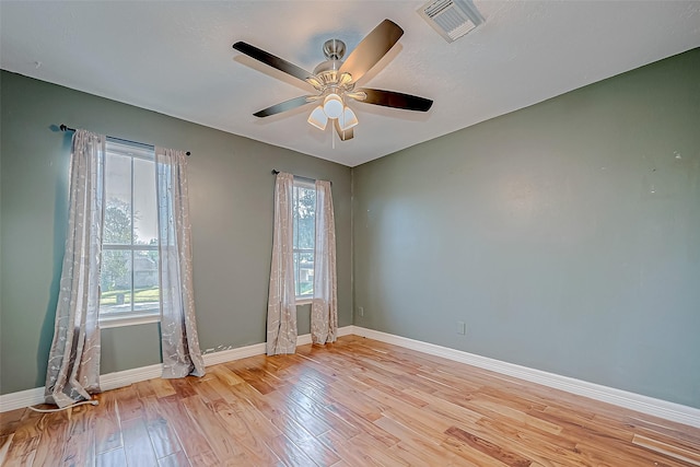 empty room with ceiling fan, a healthy amount of sunlight, and light hardwood / wood-style flooring