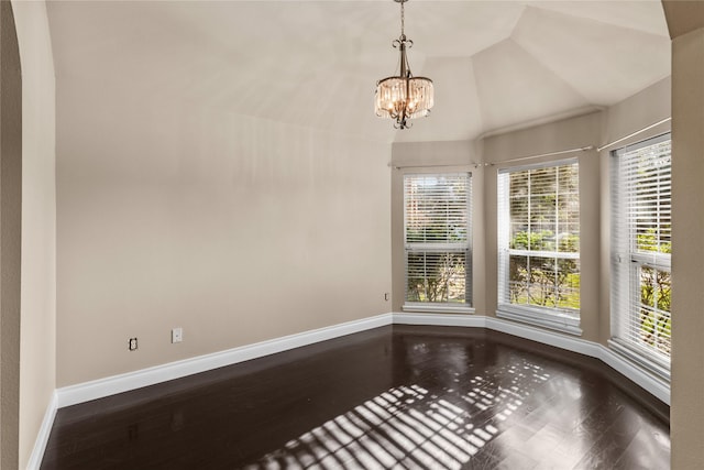 spare room featuring hardwood / wood-style flooring, an inviting chandelier, and vaulted ceiling