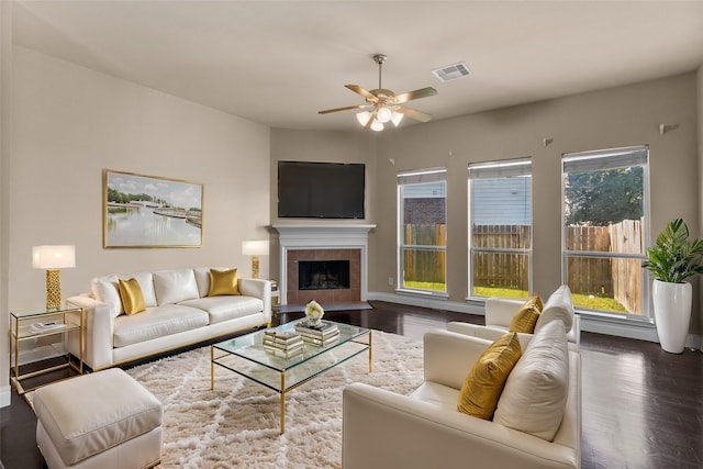 living room featuring dark wood-type flooring, a tile fireplace, and plenty of natural light