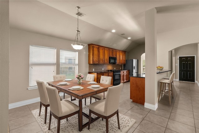 tiled dining room featuring vaulted ceiling