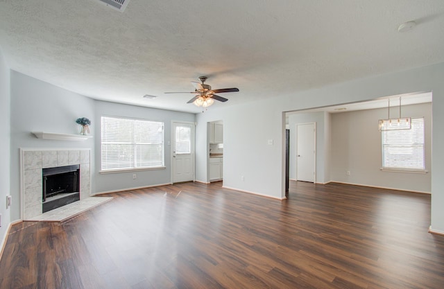 unfurnished living room with dark hardwood / wood-style floors, ceiling fan, and a tiled fireplace