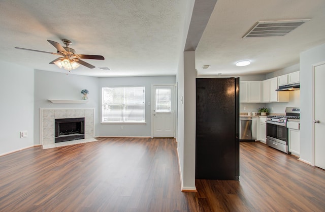 kitchen with ceiling fan, a fireplace, white cabinetry, appliances with stainless steel finishes, and dark hardwood / wood-style flooring