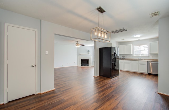 kitchen with pendant lighting, white cabinets, a fireplace, black fridge, and stainless steel dishwasher