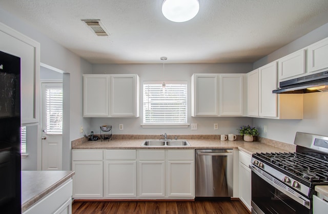 kitchen with a textured ceiling, white cabinets, appliances with stainless steel finishes, dark hardwood / wood-style flooring, and sink