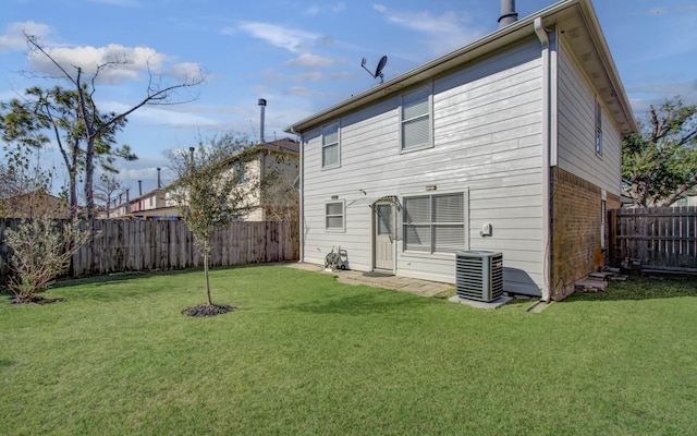 back of house featuring central air condition unit and a yard