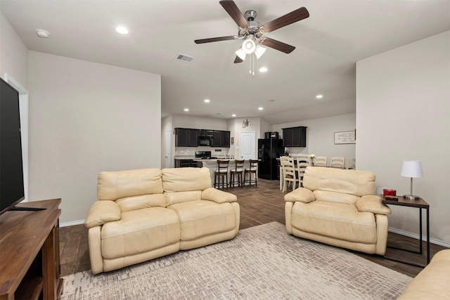 living room with ceiling fan and dark wood-type flooring