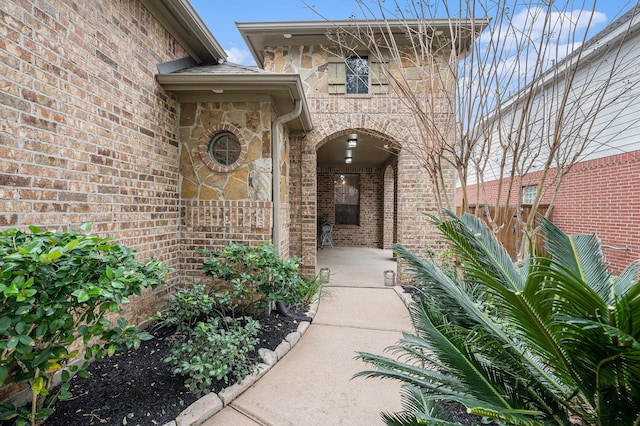 view of exterior entry featuring stone siding and brick siding