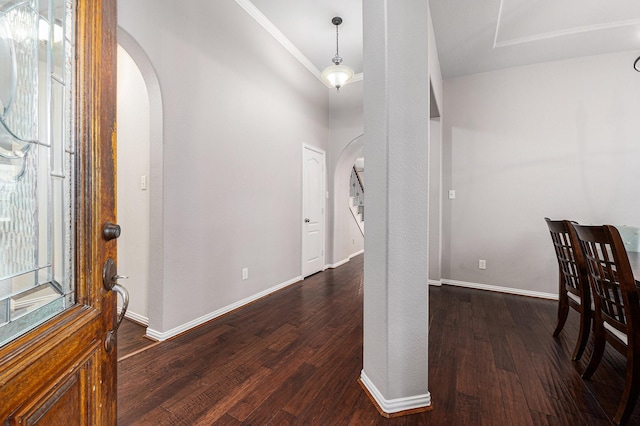 foyer with arched walkways, dark wood-style floors, and baseboards