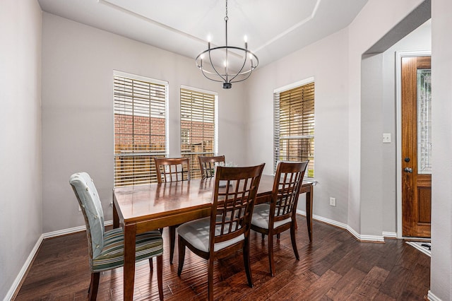 dining space featuring dark wood-style floors, baseboards, a tray ceiling, and an inviting chandelier