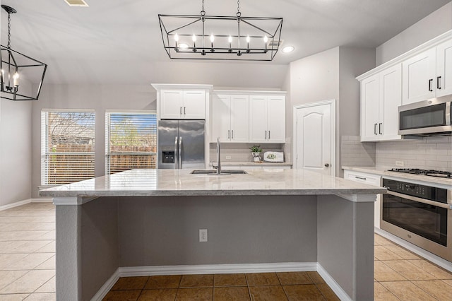 kitchen with stainless steel appliances, a sink, a kitchen island with sink, and pendant lighting