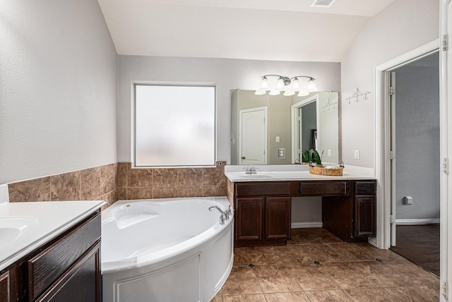 full bath with lofted ceiling, a garden tub, two vanities, a sink, and visible vents