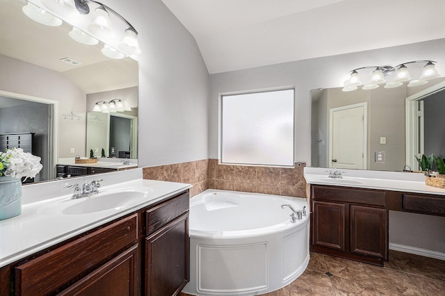 bathroom featuring lofted ceiling, two vanities, a sink, and a garden tub