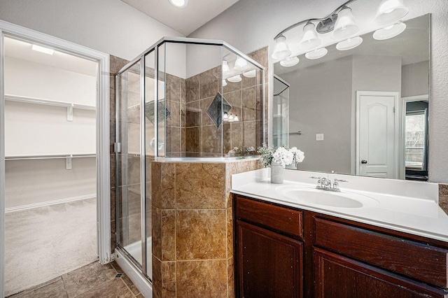 full bath featuring a stall shower, a walk in closet, and vanity