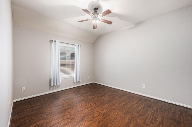 empty room featuring dark wood-type flooring, lofted ceiling, baseboards, and a ceiling fan