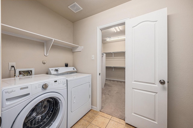 clothes washing area featuring laundry area, light tile patterned floors, visible vents, light colored carpet, and washer and dryer