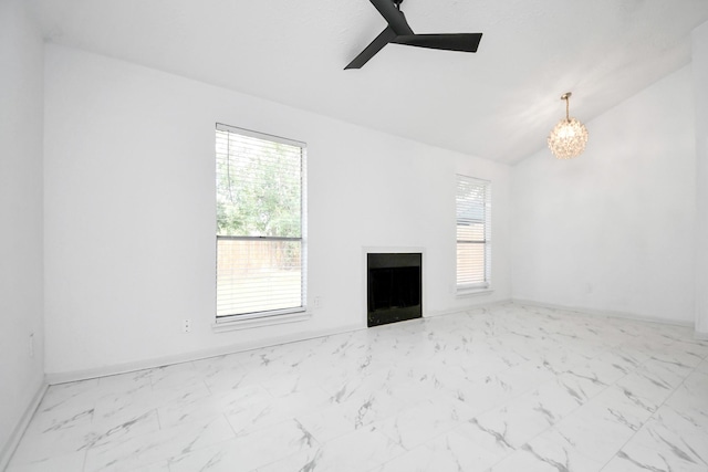 unfurnished living room featuring ceiling fan with notable chandelier and vaulted ceiling