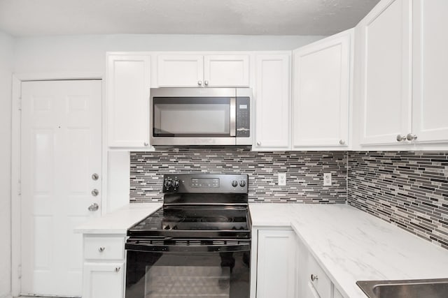 kitchen with light stone counters, white cabinets, electric range, and decorative backsplash