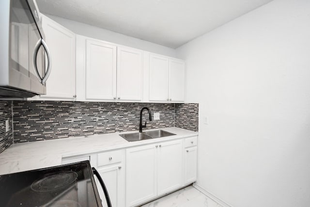 kitchen with range with electric stovetop, tasteful backsplash, white cabinetry, and sink