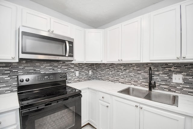 kitchen featuring sink, tasteful backsplash, white cabinets, and black / electric stove