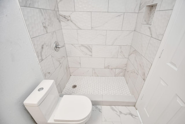 bathroom featuring a tile shower and toilet