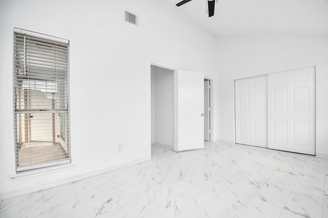 unfurnished bedroom with high vaulted ceiling, a closet, and ceiling fan