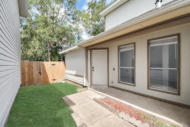 view of exterior entry with a patio and a lawn