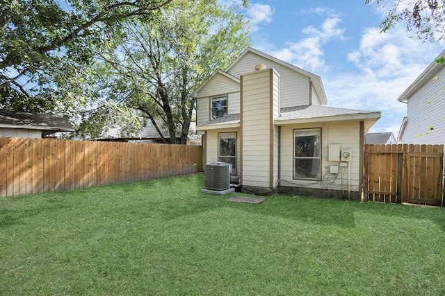 rear view of property with central air condition unit and a yard