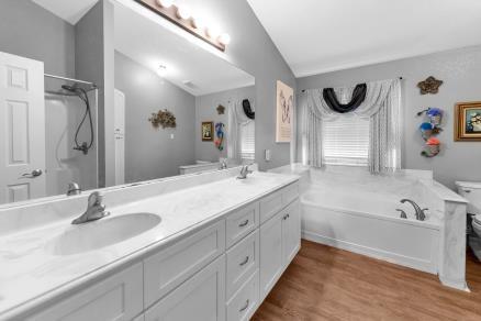 full bathroom with vaulted ceiling, wood-type flooring, toilet, vanity, and shower with separate bathtub