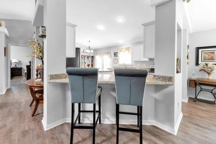 kitchen featuring a kitchen breakfast bar, white cabinetry, light stone countertops, kitchen peninsula, and light hardwood / wood-style flooring