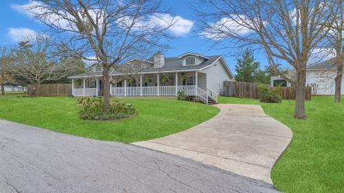 cape cod home featuring a porch, a front lawn, and fence