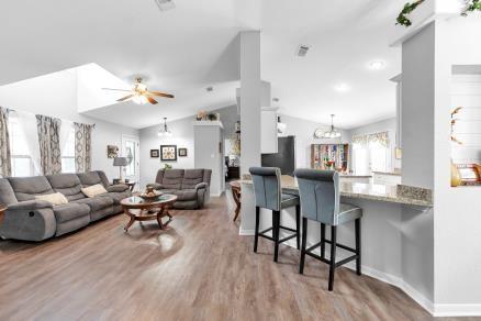 living room featuring ceiling fan, vaulted ceiling, and light wood-type flooring